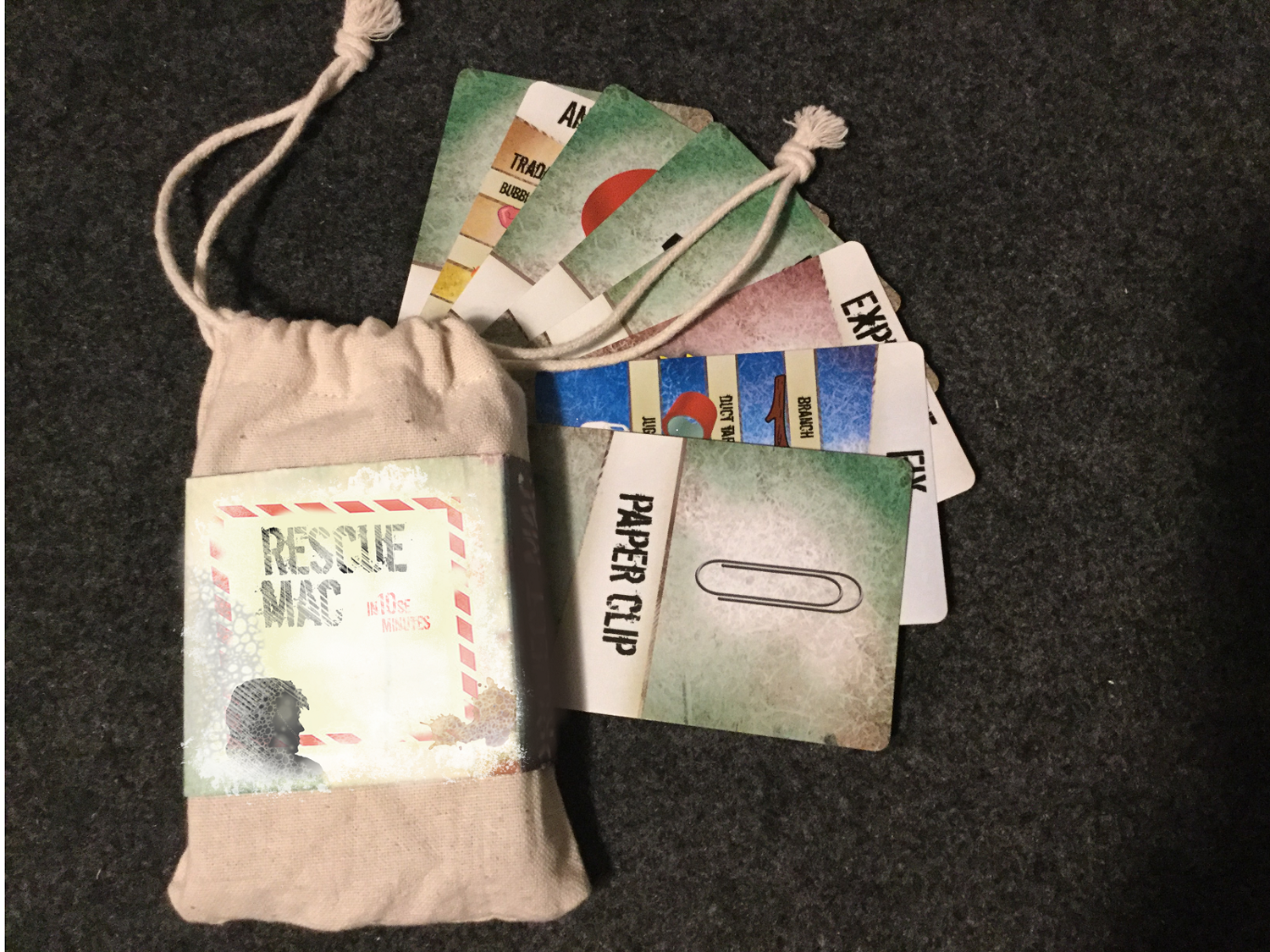 Rescue Mac drawstring bag with item cards fanned out beside it, including a Paper Clip card.